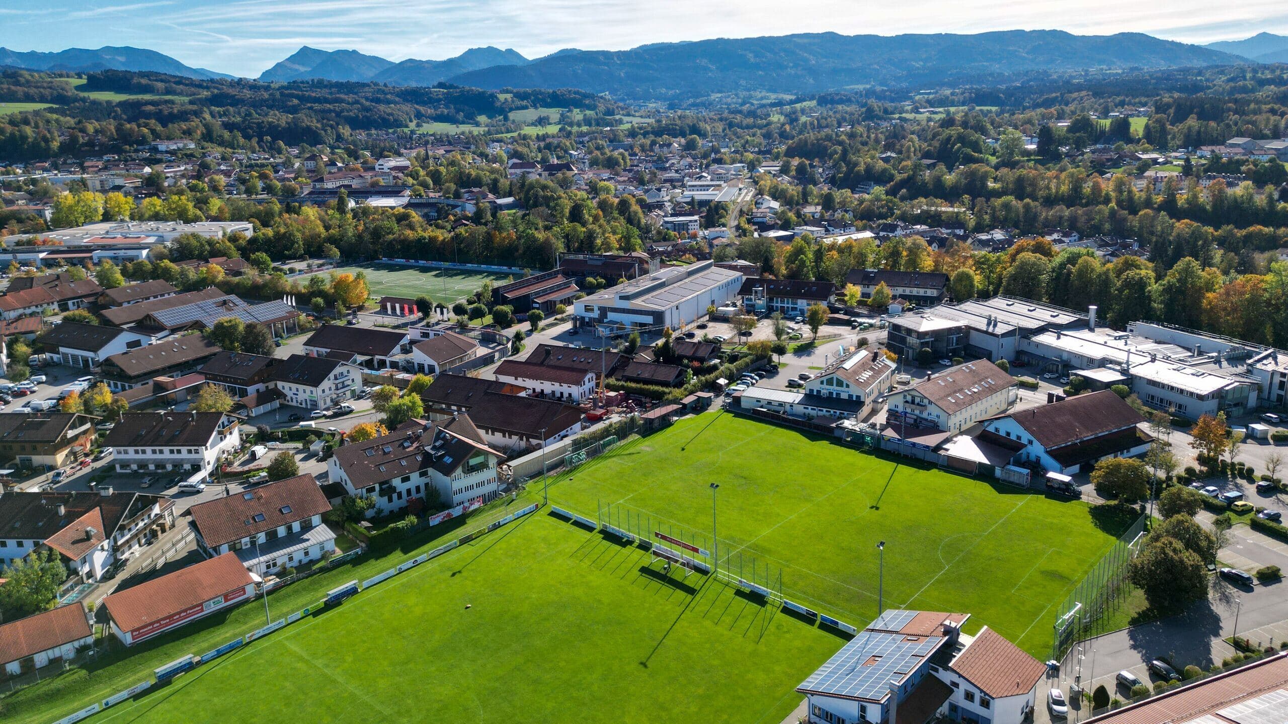 Luftbild Am Windfeld: vorn Hauptplatz und Nebenplatz mit Vereinsheim, dahinter der Kunstrasen, Miesbach und die Berge