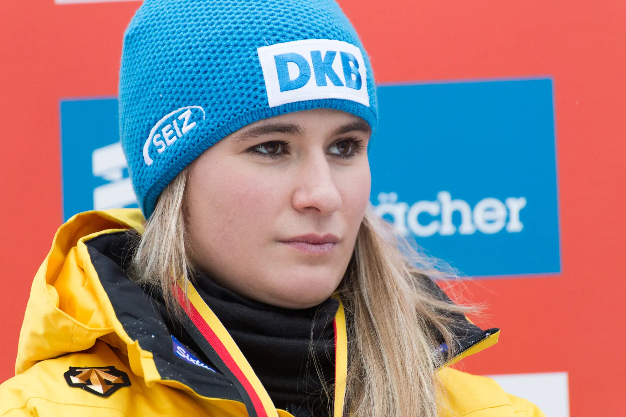 Porträt von Natalie Geisenberger mit blauer Mütze und gelber Teamjacke beim Weltcup in Oberhof