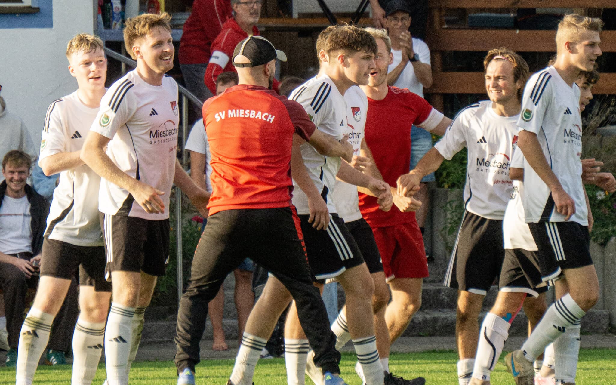 Spieler und Betreuer der Zweiten des SV Miesbach feiern vor dem Vereinsheim am Windfeld