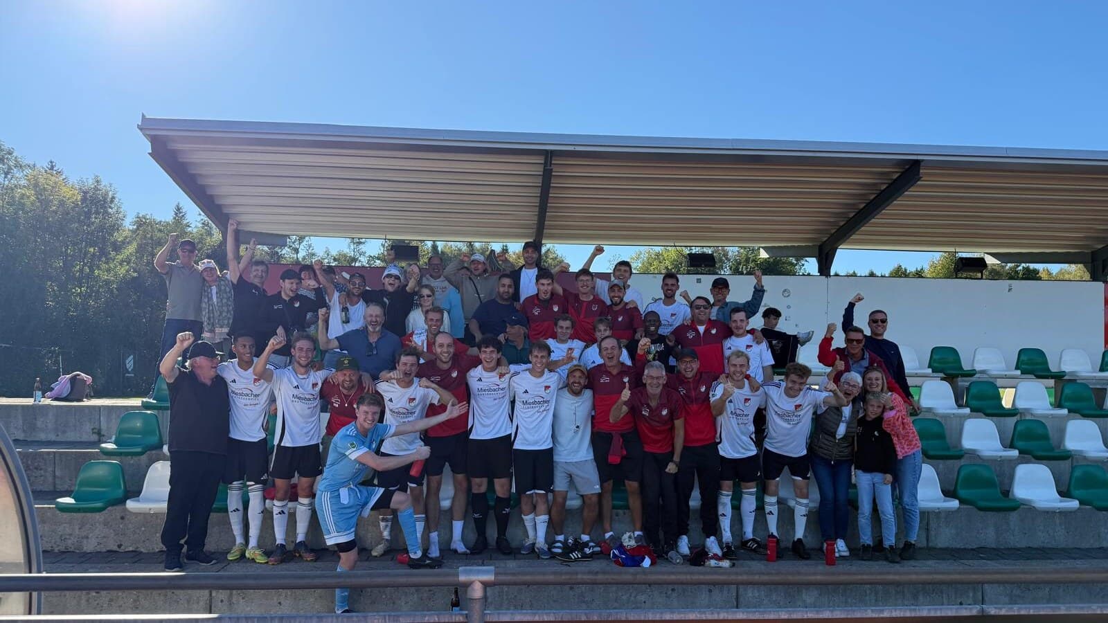 Spieler, Trainer und Fans des SV Miesbach jubeln nach dem 2:1-Sieg beim SB DJK Rosenheim auf der Tribüne